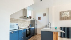 A modern kitchen with blue cabinets, a built-in oven, a microwave, and a sink. - Gite in the heart of Saône et Loire (DOMPIERRE LES ORMES)