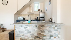 A kitchen with a stone backsplash, a microwave, a stainless steel refrigerator, and a sink. - Gite in the heart of Saône et Loire (DOMPIERRE LES ORMES)