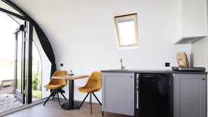Une cuisine compacte équipée d’un lave-vaisselle intégré, d’une petite table, de deux chaises et d’une fenêtre.