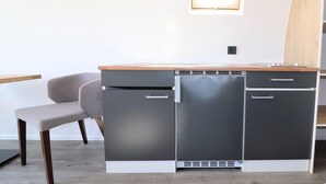 Une petite cuisine équipée d’un réfrigérateur intégré, d’un four à micro-ondes et d’un évier.