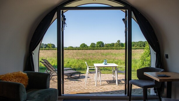 Une pièce dotée d’une grande fenêtre en arc de cercle, d’une table avec des chaises et d’un canapé.