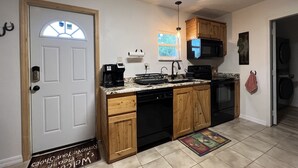 A compact kitchen with wooden cabinets, a built-in dishwasher, and a coffee maker. - Horsing Around In the country (Dade City)