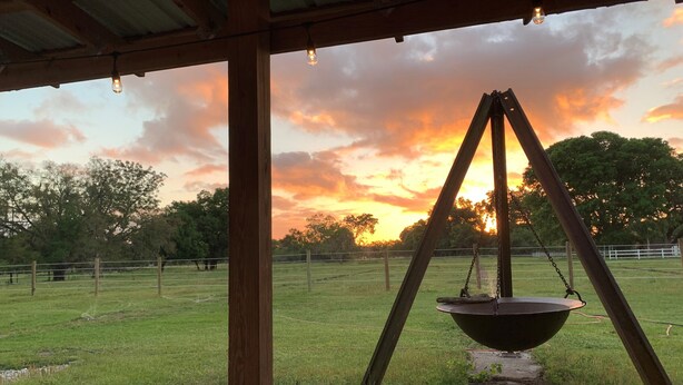 A wooden structure with a swing set and a hanging light fixture. - Horsing Around In the country (Dade City)