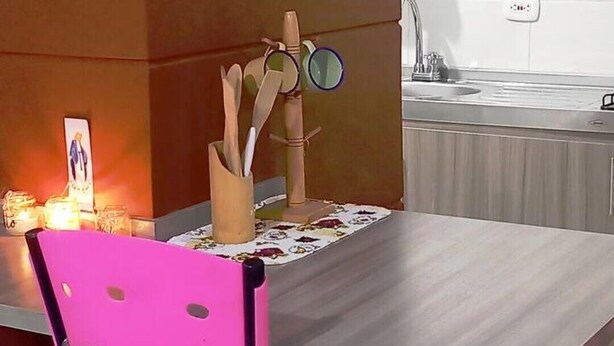 Een keuken met een houten kast, een tafel met een onderzetter en een stoel.