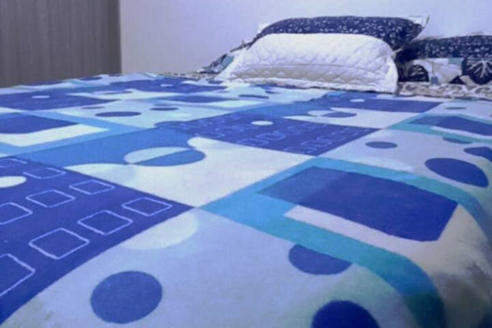 A bed with a blue and white patterned bedspread.