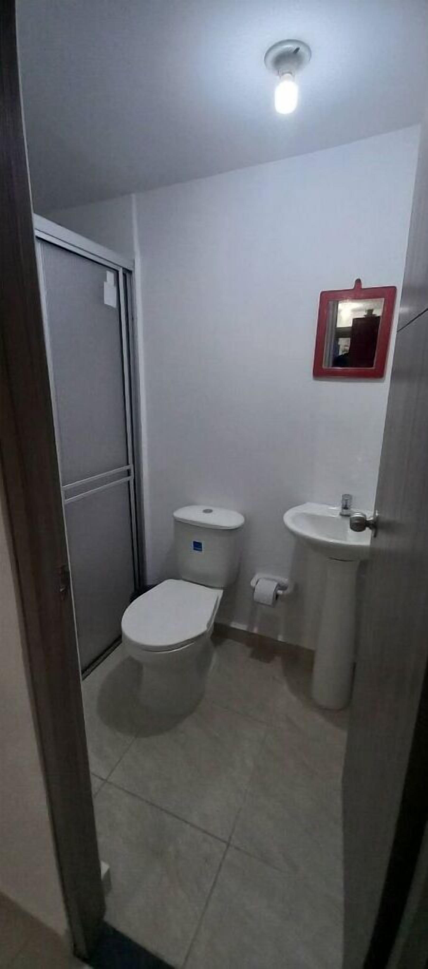A small, compact bathroom with a toilet, sink, and mirror.