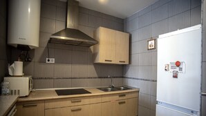 Cocina equipada con microondas, pileta y campana extractora de acero inoxidable.