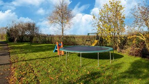 A grassy outdoor area with a trampoline, a slide, and a swing set. - Eco-friendly apartment with a garden (Sint Kruis)