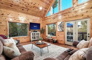 Relax in this spacious living room with a high ceiling, large windows, and a comfortable seating area featuring a sofa and coffee table.