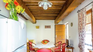 A dining area with a table, chairs, a vase of flowers, and a ceiling fan.