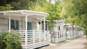A row of white mobile homes with attached porches, surrounded by greenery. - Charming Coastal Stay (Cesenatico)