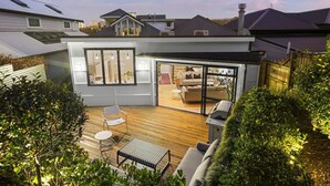A modern house with a spacious patio, a dining area, and a large sliding glass door leading to an interior living space. - Elite Retreat Ponsonby with Parking and Deck (Auckland Central Suburbs)
