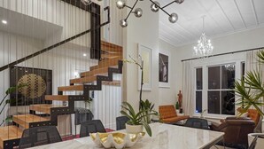 A modern interior with a dining area, a staircase, and a chandelier. - Elite Retreat Ponsonby with Parking and Deck (Auckland Central Suburbs)
