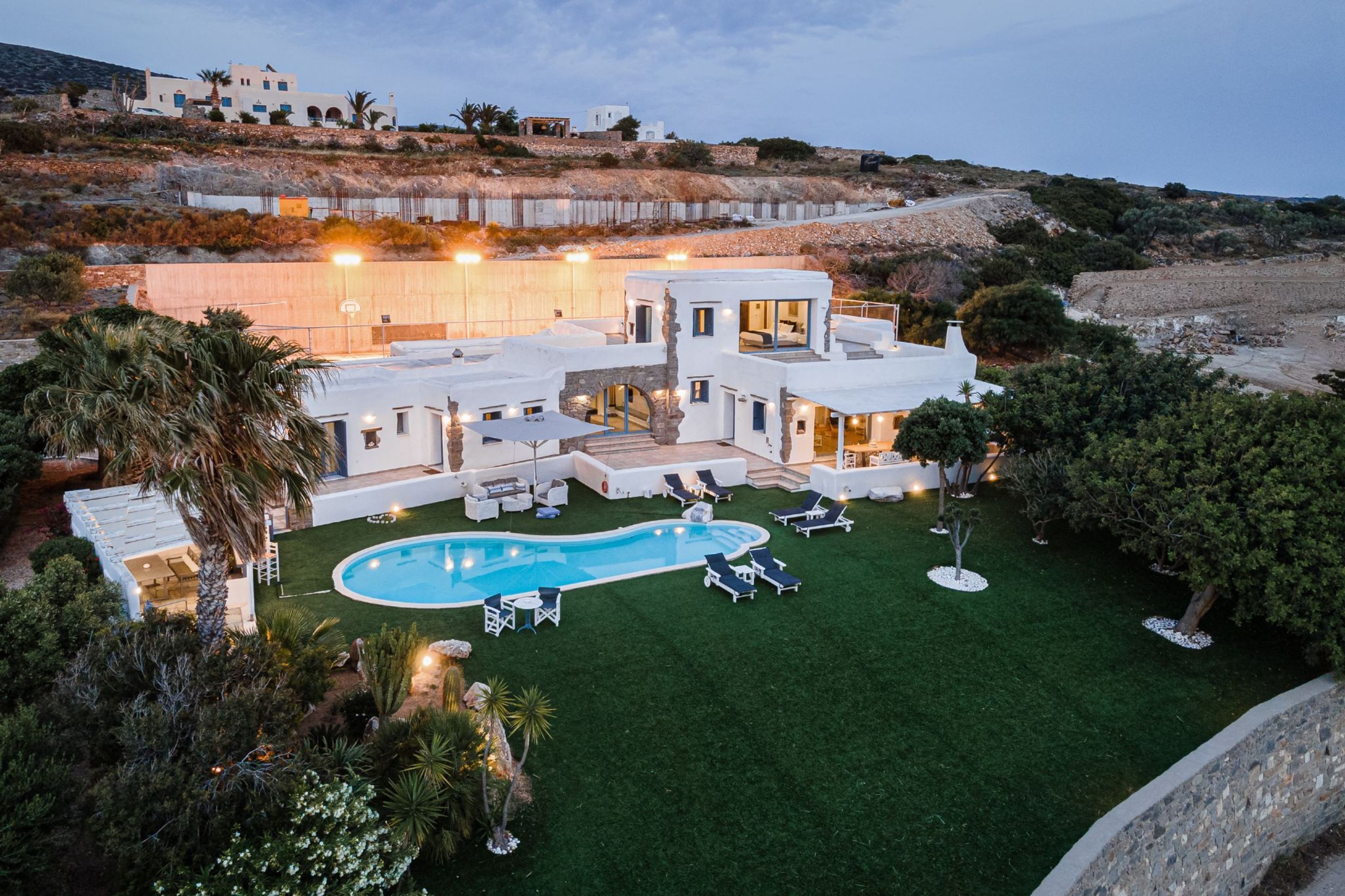 Eine moderne Villa mit Swimmingpool, Sitzgelegenheiten im Freien und Blick auf die umliegende Landschaft.