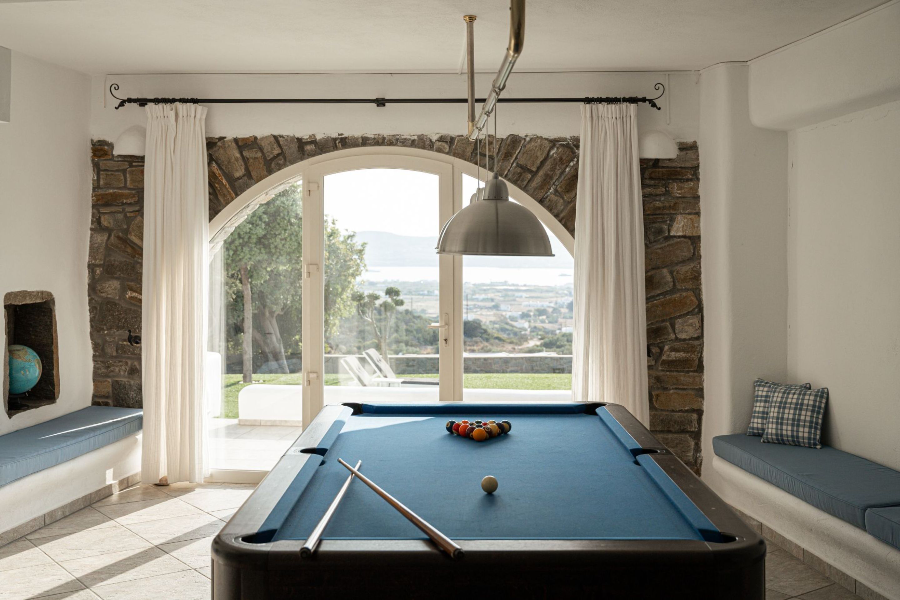 Uma mesa de bilhar com vista para uma parede de pedra e um banco.