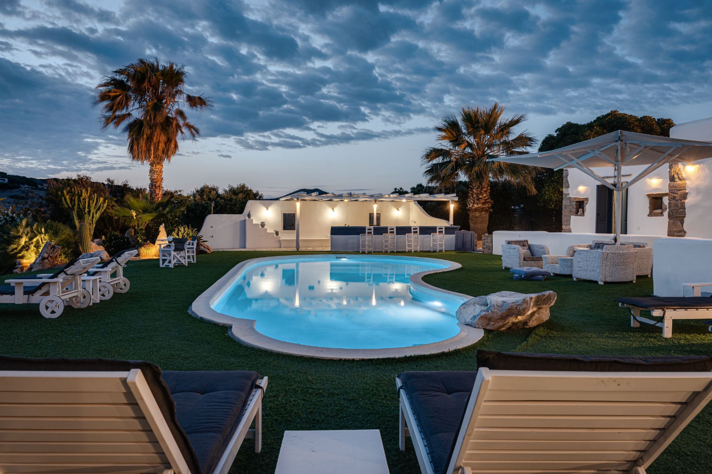 A pool area with lounge chairs, a bar, and a covered seating area.