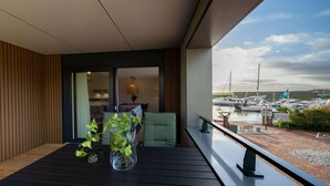 Ein Balkon mit Blick auf eine Marina, ein Essbereich mit Tisch und Stühlen sowie ein Blumentopf.