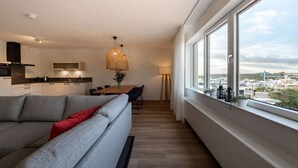 Ein modernes Apartment mit einem großen Fenster, einem Essbereich und einer Küche.