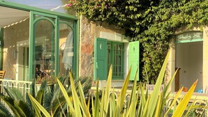 A building with green shutters, a glass door, and a balcony with plants.