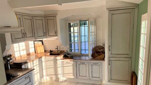 A kitchen with white cabinets, a window with a view, and a countertop with various items.
