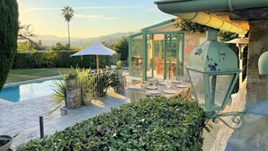A glass-enclosed patio with outdoor furniture, a pool, and a lantern.