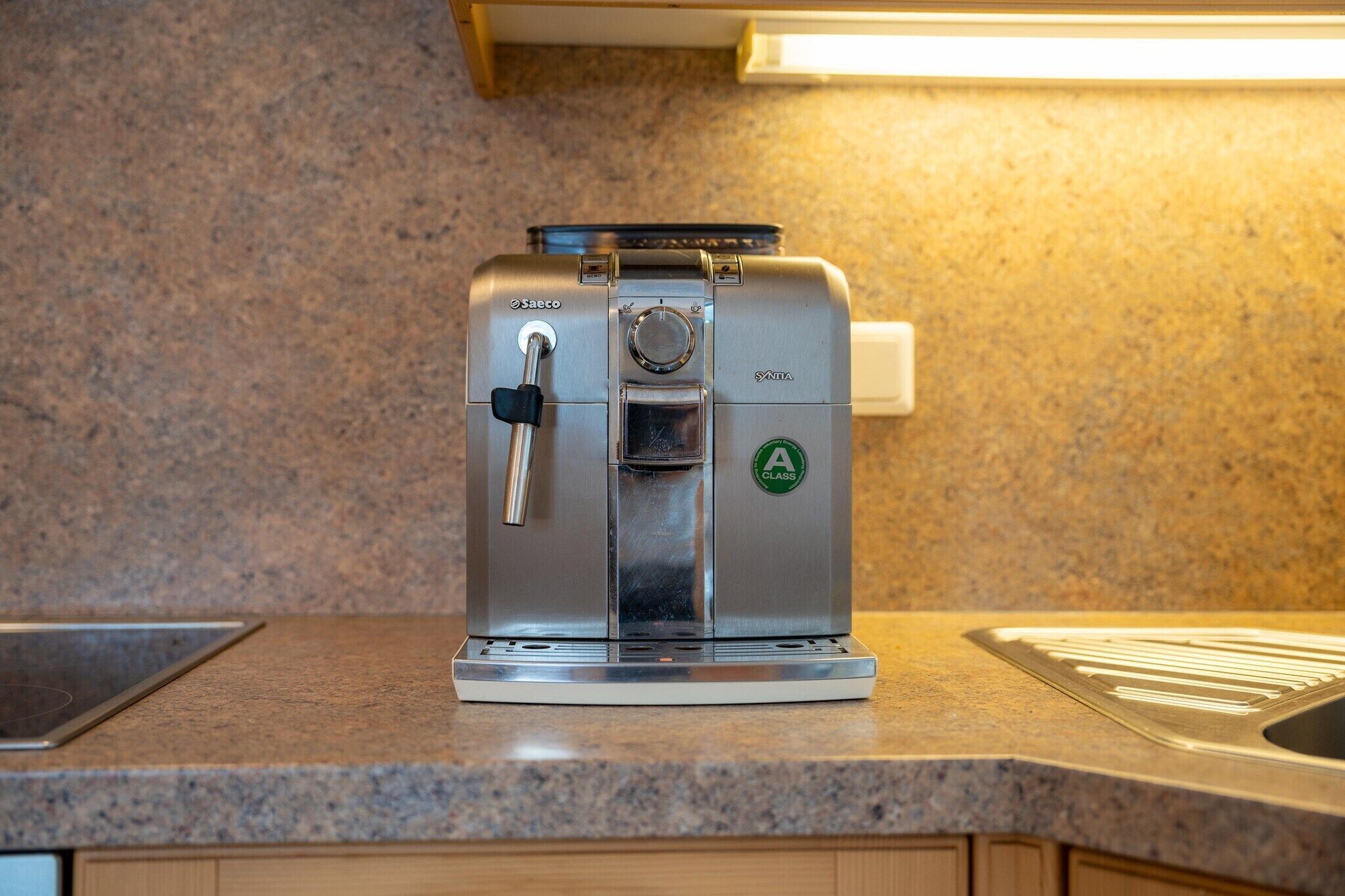 Una macchina da caffè espresso in acciaio inossidabile su un piano di lavoro in granito in una cucina.