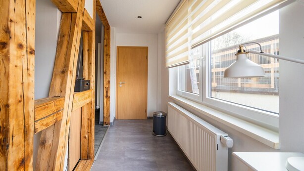 A hallway with wooden beams, a radiator, a window with blinds, and a door. - Rückzugsort mit Waldblick (Zella-Mehlis)