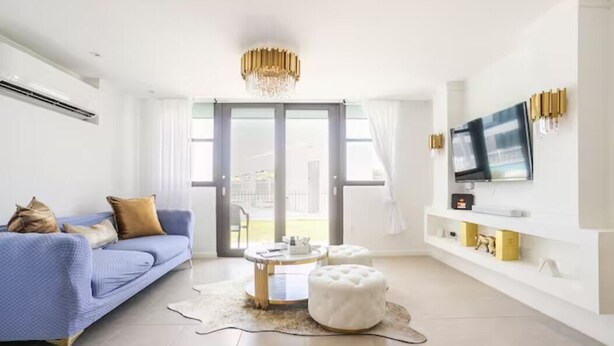 Een moderne woonkamer met een blauwe bank, een ronde salontafel en een witte voetenbank.