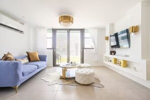 Un salon moderne avec un canapé bleu, une table basse ronde et un pouf blanc.
