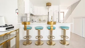 Een moderne keuken met witte kasten, een backsplash met een visgraatmotief en een centraal eiland met barkrukken.