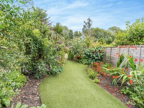 A garden pathway with various plants and flowers.