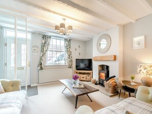 A living room with a fireplace, a television, a wooden coffee table, and a sofa.