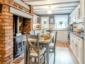 A kitchen with a brick wall, wooden table, chairs, and a window with a view.
