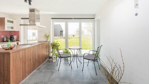 A modern kitchen with a wooden countertop, a built-in stove, and a large window. - Charming Cottage with Sauna (Honnelles)