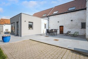 A courtyard with a modern building, a traditional building with a tiled roof, and outdoor seating.