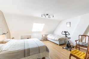 A bedroom with a bed, a desk, a chair, an exercise bike, and a window.