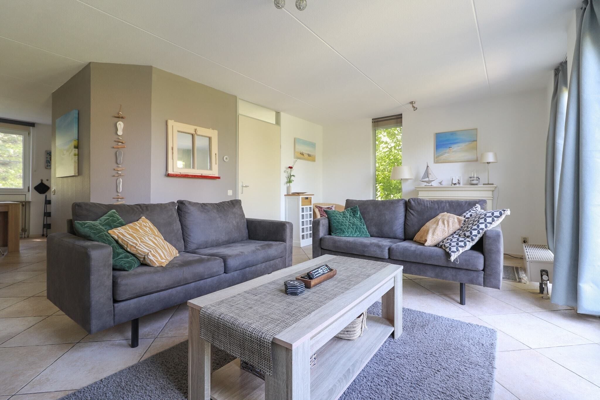 Ein modernes Wohnzimmer mit zwei grauen Sofas, einem Holztisch und einem grauen Teppich.