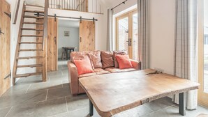 A loft-style room with a wooden staircase, a large table, and a sofa with cushions. - The Red Rooster - UK44440 (Arlingham, near Frampton-on-Severn)