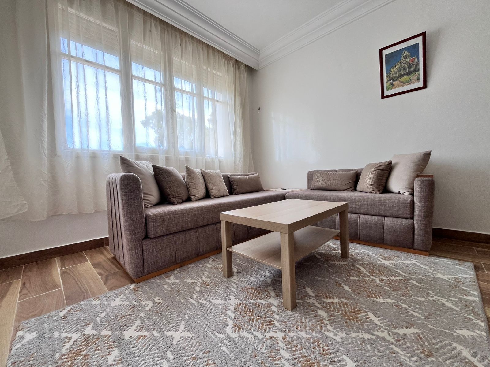 Ein Wohnzimmer mit einem Ecksofa, einem Couchtisch und einem gemusterten Teppich.
