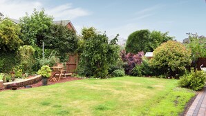 Un jardin bien entretenu, agrémenté d’une terrasse en bois, d’une variété de plantes et offrant une vue sur un ciel dégagé.