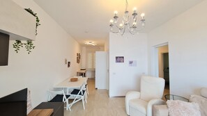 A modern living room with a dining area, a chandelier, and a white sofa.