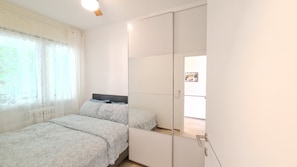A bedroom with a bed, a wardrobe, and a window with curtains.