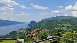 A mountainous landscape with a lake, a pool, and buildings with red roofs. - Casa Irene le Balze apartment lake view (Tremosine)
