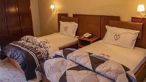 A hotel room with two single beds, each with a headboard, bedside tables, and lamps. - Fono Hôtel (Yaoundé)