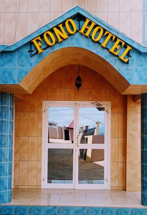 The entrance to Fono Hotel with a tiled facade and a large arched doorway.