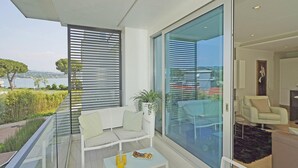 A modern balcony with a glass door, white furniture, and a table with drinks. - Bristol Exclusive 2 5 by Wonderful Italy (Lonato del Garda)