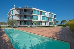 Un immeuble moderne à plusieurs étages, avec une piscine située devant.