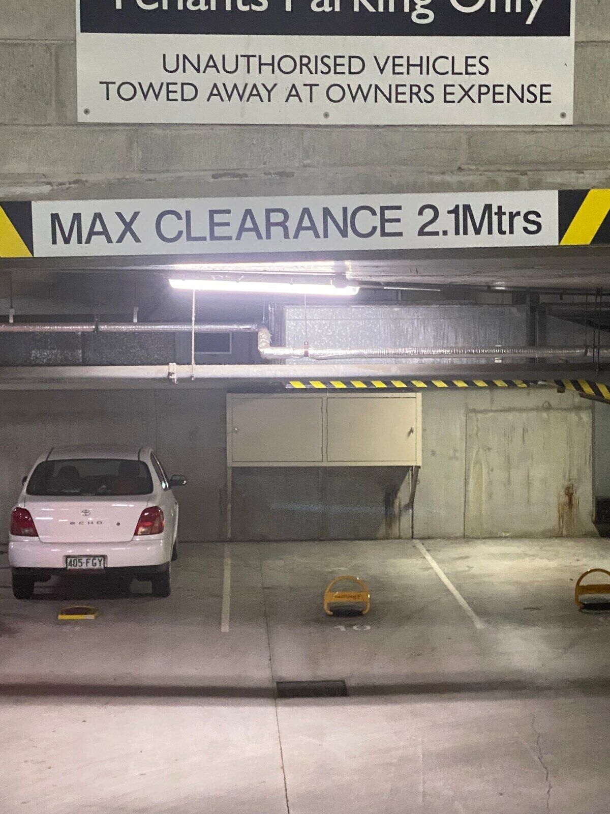 Un parking avec un panneau indiquant « Réservé aux locataires » et un avertissement précisant que tout véhicule non autorisé sera remorqué aux frais du propriétaire. La hauteur maximale autorisée est de 2,1 mètres.