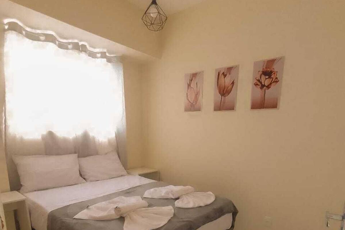 A bedroom with a bed, a bedside table, a hanging light fixture, and three wall-mounted pictures.