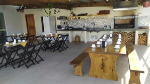 A rustic kitchen with a long wooden table set for dining, a refrigerator, microwave, and a built-in oven. - Residencial Terrazas (Florianópolis)